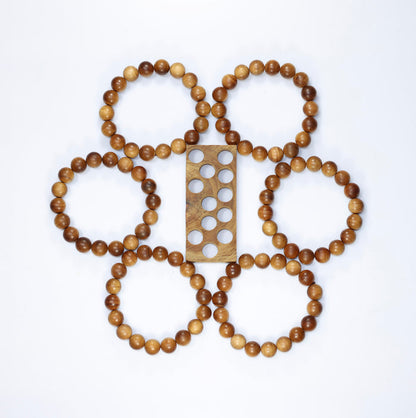Buy natural sandalwood bracelet collection arranged around a wooden bead-sizing board