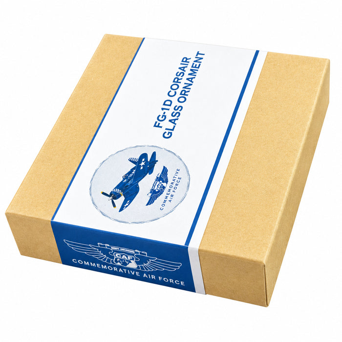 A square product box with a kraft beige exterior and a white wrap label featuring blue text that reads 'FG-1D Corsair Glass Ornament'