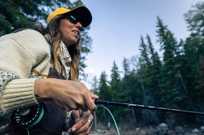 Person fly fishing in a forested area